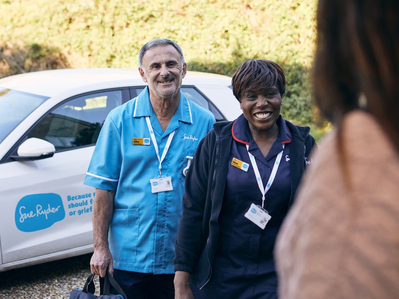 A female Sue Ryder Nurse and a male Sue Ryder Nurse at the front door of a patient