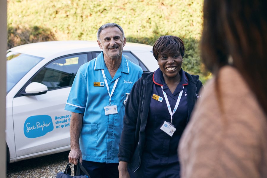 A female Sue Ryder Nurse and a male Sue Ryder Nurse at the front door of a patient