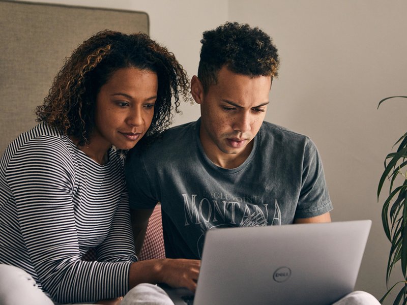 An adult and a young person sit together looking at a laptop.