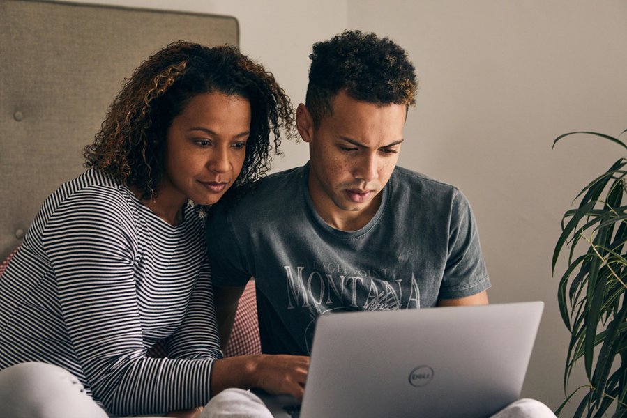 An adult and a young person sit together looking at a laptop.