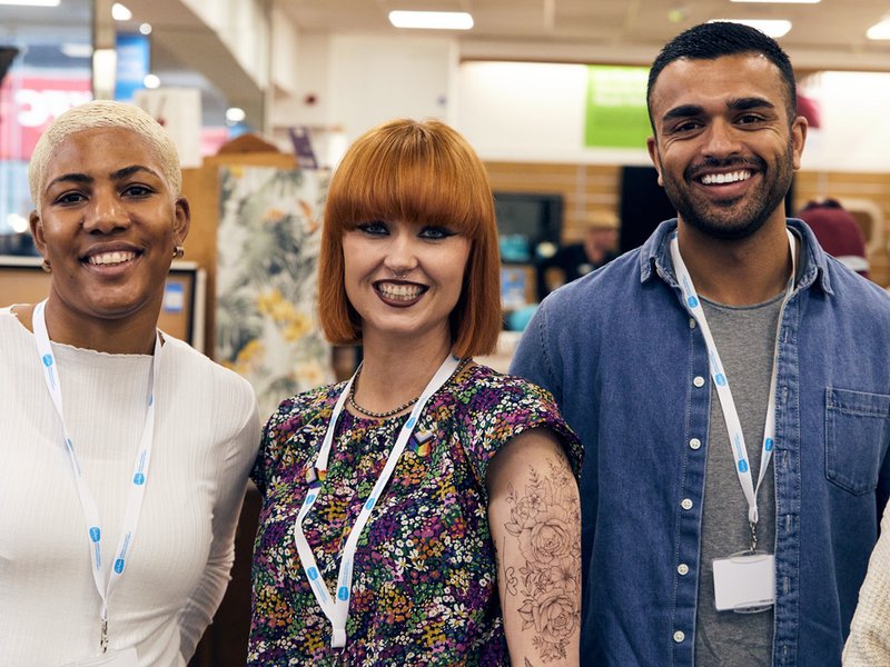 Three shop assistants and volunteers smile towards the camera