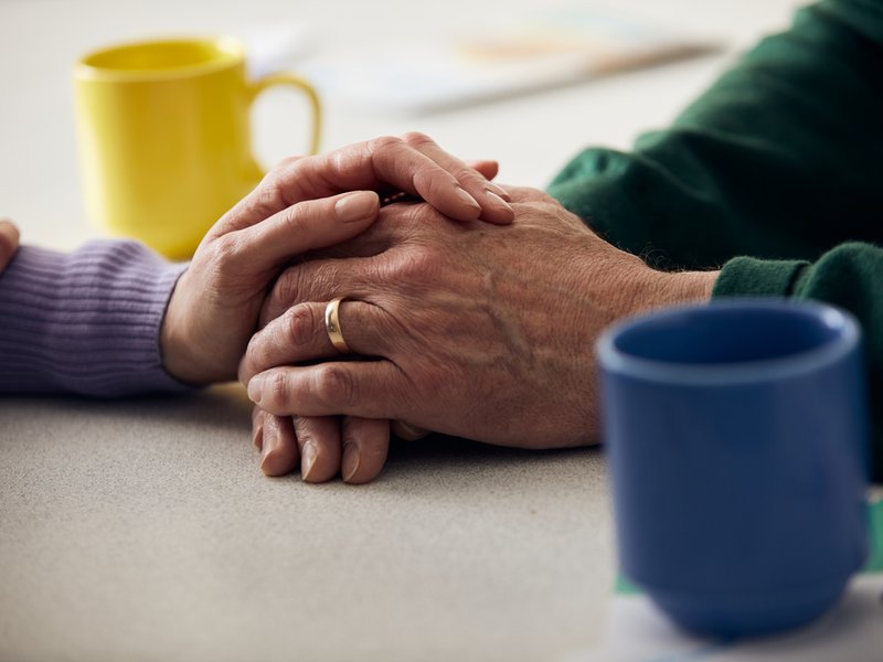 Image focused on the clutched hands of two people, with mugs around them.