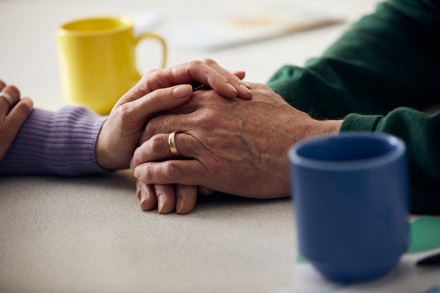 Image focused on the clutched hands of two people, with mugs around them.