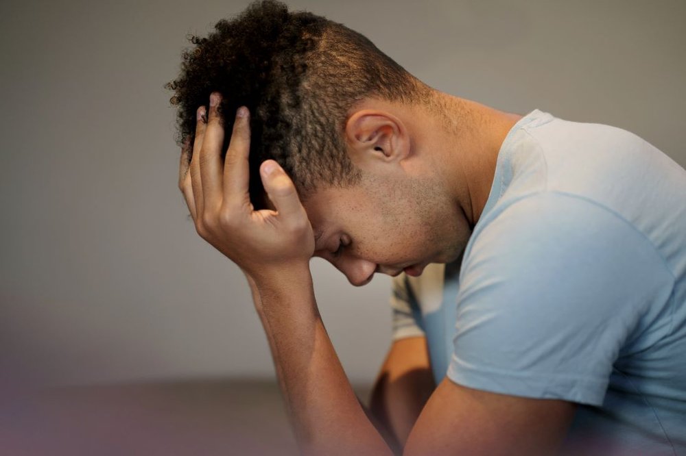 A young person sits with his head in his hands