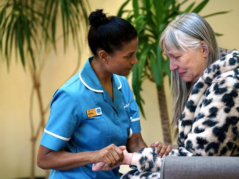 A Sue Ryder Nurse comforting a patient and holding their hand