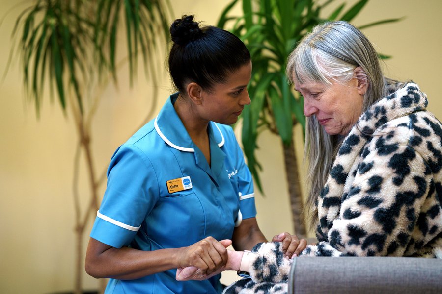 A Sue Ryder Nurse comforting a patient and holding their hand