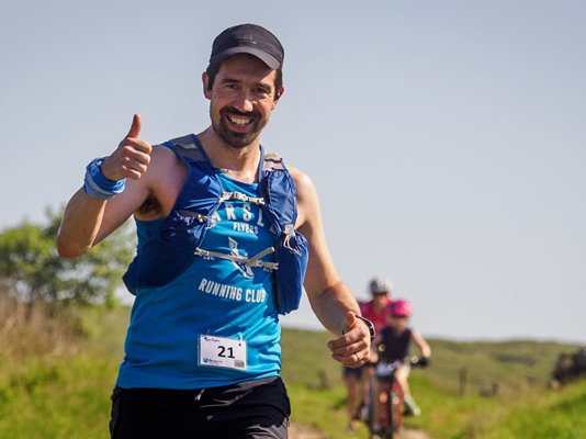 A runner during the Bronte Half Marathon race, smiling and giving the thumbs up