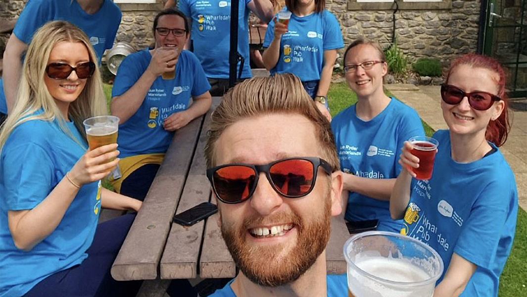 A group of walkers enjoying some drinks outside at a pub bench in the sun
