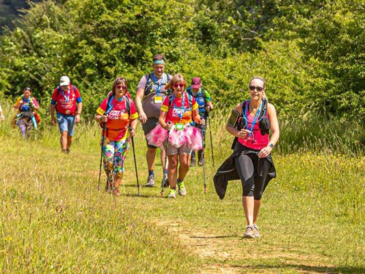 Walkers and runners surrounded by green fields along the Cotswold Way Challenge route