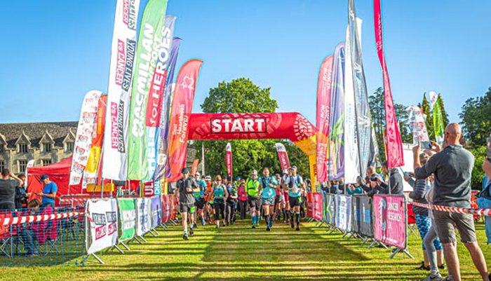 Runners at the starting line, surrounded by supporters and charity banners