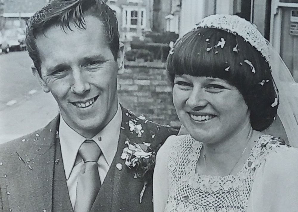 Black and white photo of younger Debbie and Doug smiling at the camera covered in confetti.