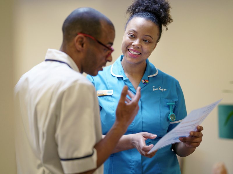 Two healthcare professionals are talking and looking at a piece of paper together