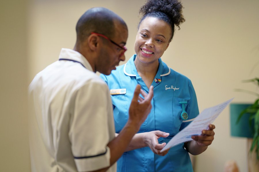 Two healthcare professionals are talking and looking at a piece of paper together