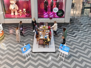 Sue Ryder's Empty Chair Exhibit in Leeds Shopping Centre, where a dining table is set up with empty places to represent loved ones who have died