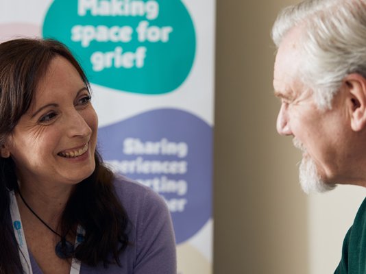 A Grief Kind Space volunteer talking to an attendee during a session