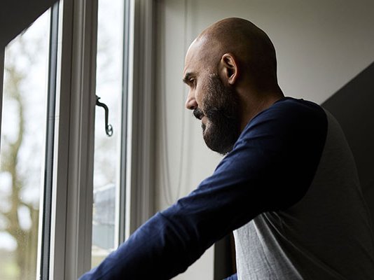 A grieving man staring out of a window
