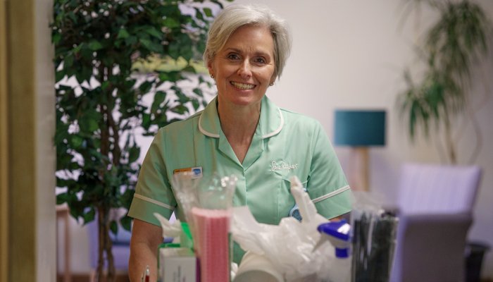 A Sue Ryder hospice volunteer pushing a trolley down a hall