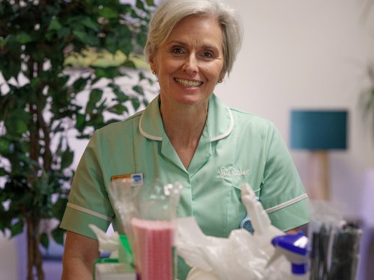 A Sue Ryder hospice volunteer pushing a trolley down a hall