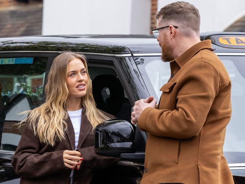 Women speaking to a man in front of a black cab