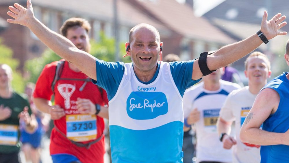 A Sue Ryder runner with their arms in the air