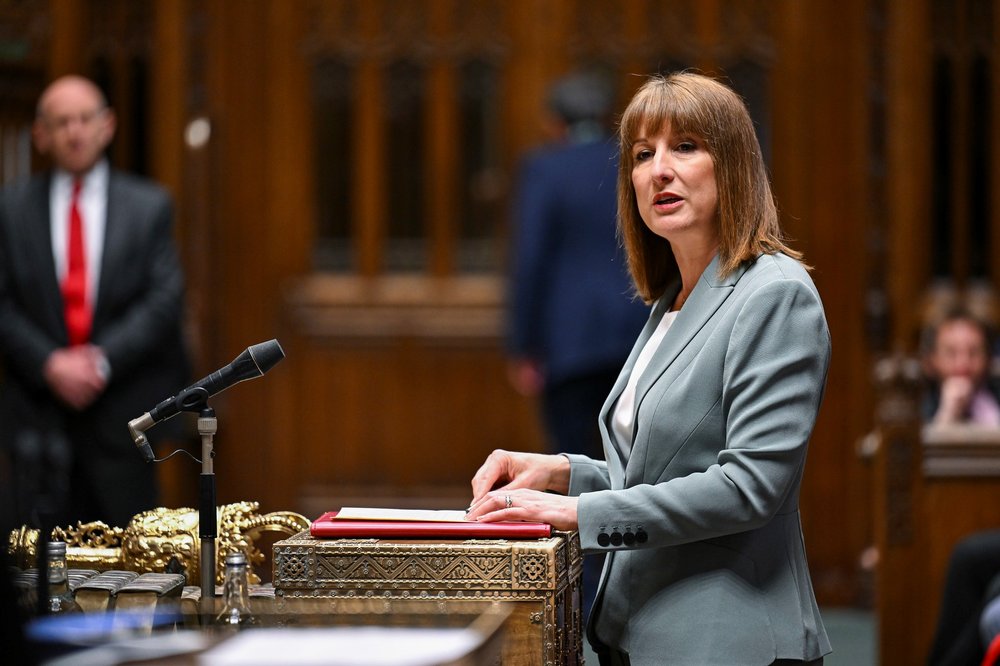 Rachel Reeves MP, stands at podium inside House of Commons, speaking with a serious facial expression