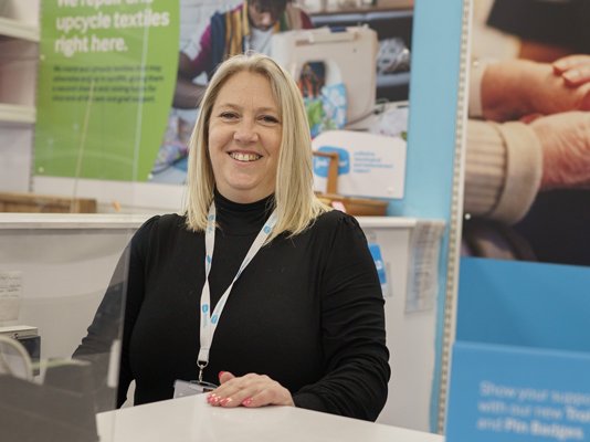 A Sue Ryder shop manager standing behind the till