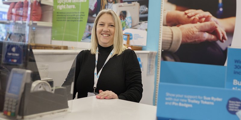 A Sue Ryder shop manager standing behind the till