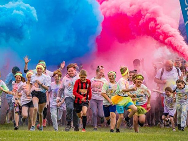 A line of runners, covered in paint at the starting line of PaintRush