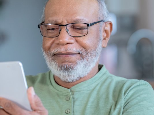 An older man holding up and looking at his phone
