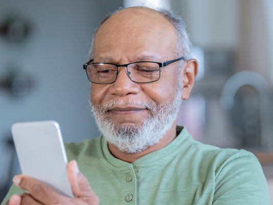 An older man holding up and looking at his phone