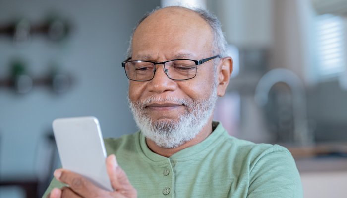 An older man holding up and looking at his phone