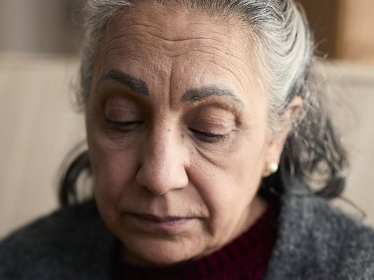 A grieving and sad older woman, looking down
