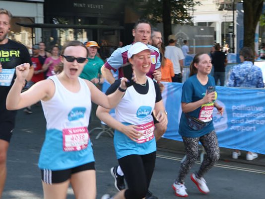 Two Sue Ryder runners racing past the cheer point during the race