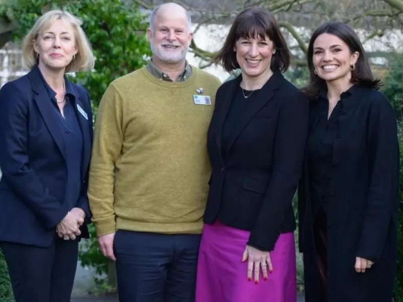 Three women and one man smile at the camera.