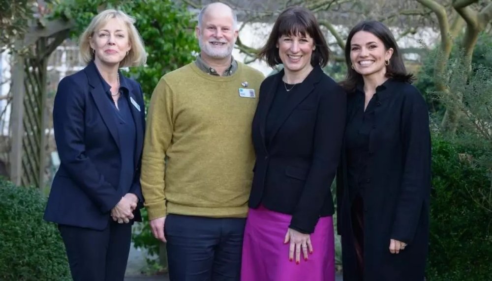 Three women and one man smile at the camera.
