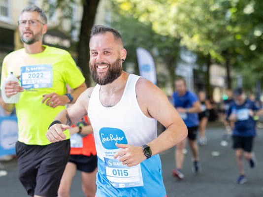 A smiling Sue Ryder runner on the race route, with others behind them