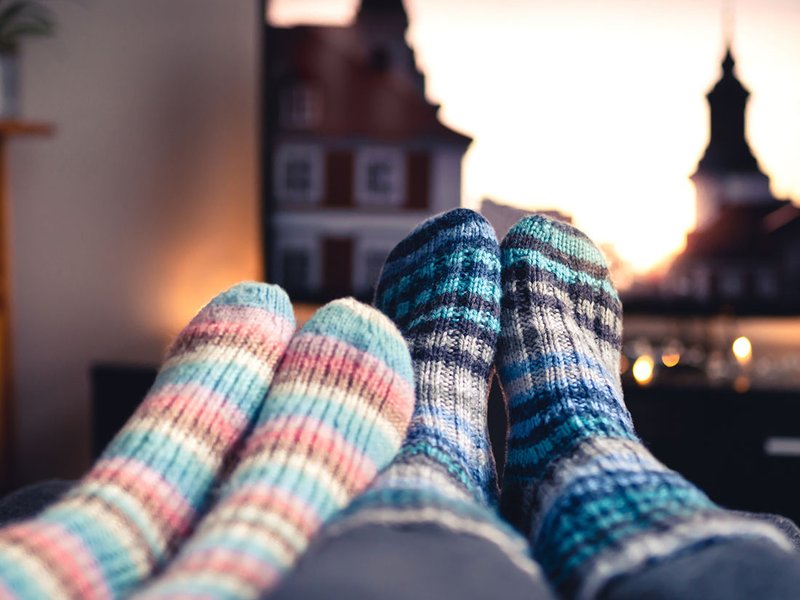 A close up of two pairs of feet in thick socks, next to each other in a living room