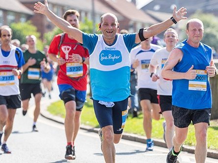 A Sue Ryder runner during a race, with his hands in the air
