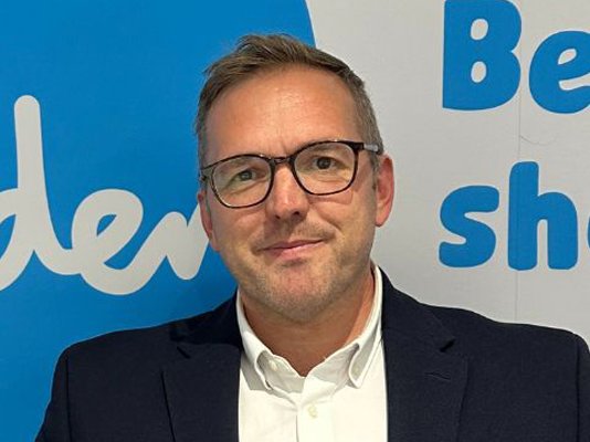 Sue Ryder CEO, James Sanderson, in front of a Sue Ryder sign