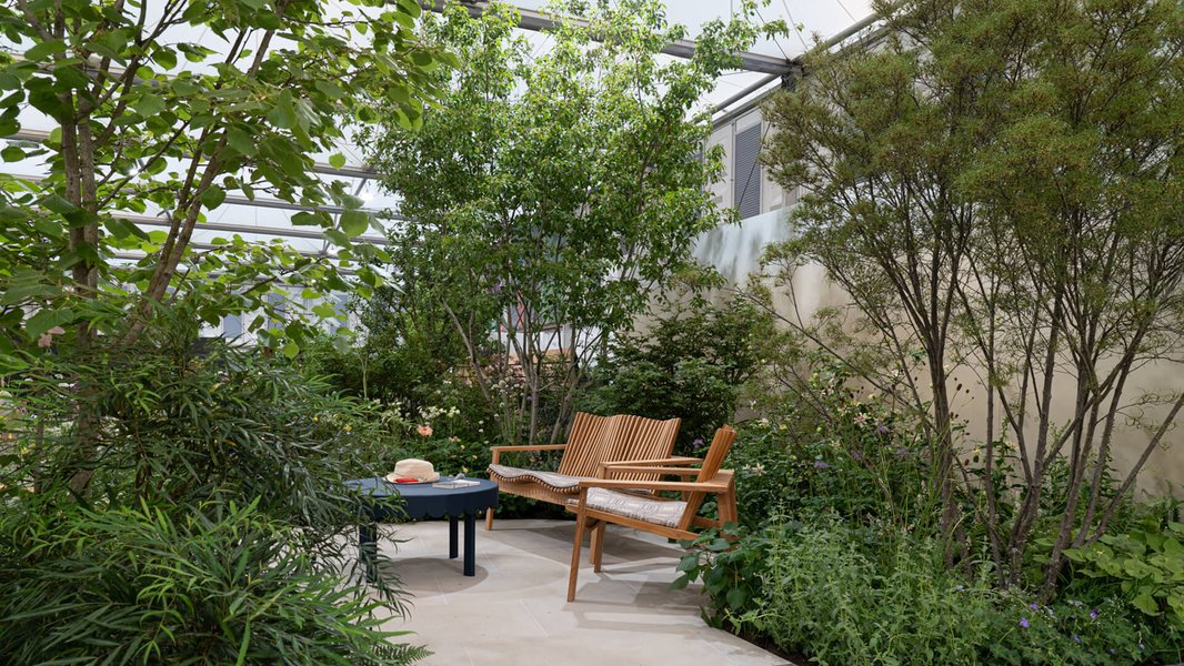 The Sue Ryder Grief Kind Garden, with wooden chairs and a table, surrounded by flowers and plants
