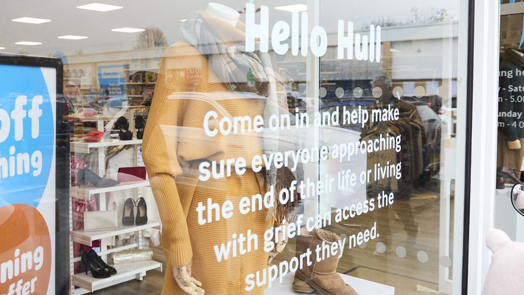 The Sue Ryder Hull shop's front window with white 'Hello Hull' text on, with a clothed mannequin and other items behind the glass