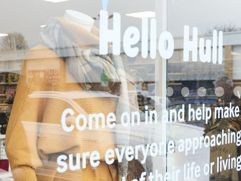 The Sue Ryder Hull shop's front window with white 'Hello Hull' text on, with a clothed mannequin and other items behind the glass