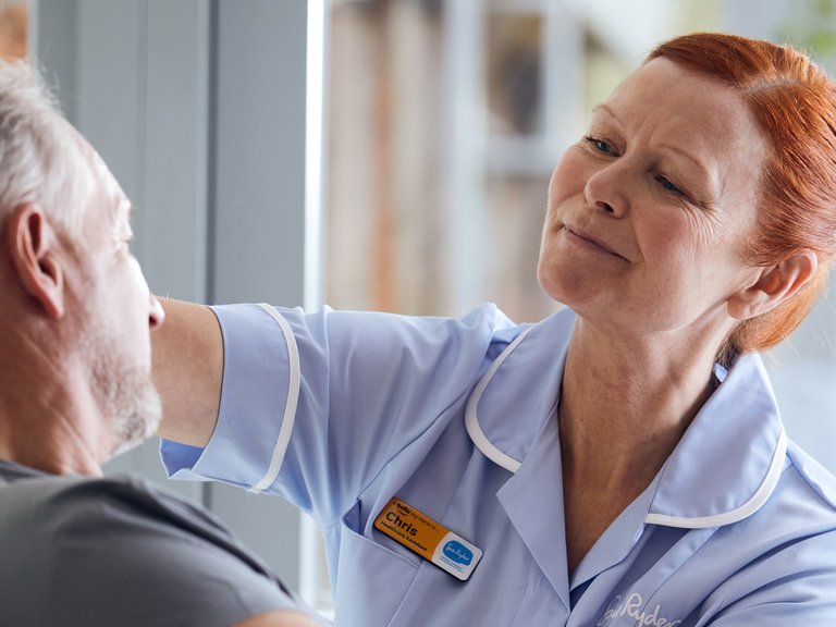 A Sue Ryder Nurse caring for a patient in their bed