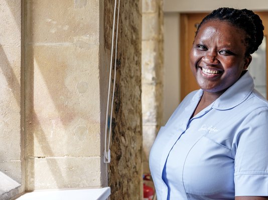 A smiling Sue Ryder Nurse near a sunny window