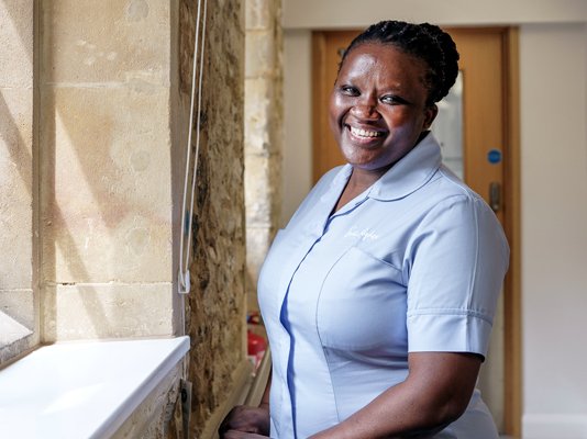 A smiling Sue Ryder Nurse near a sunny window