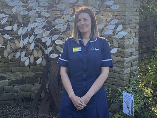 Sue Ryder Nurse, Vicki, in the Sue Ryder Manorlands Hospice garden, in front of their Memory Tree