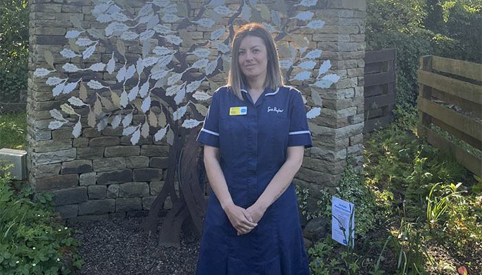 Sue Ryder Nurse, Vicki, in the Sue Ryder Manorlands Hospice garden, in front of their Memory Tree