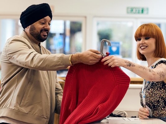 A Sue Ryder shop volunteer serving a customer buying clothing at the till