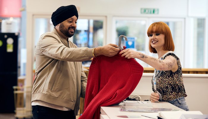 Sue Ryder shop volunteer serving a customer buying clothing at the till