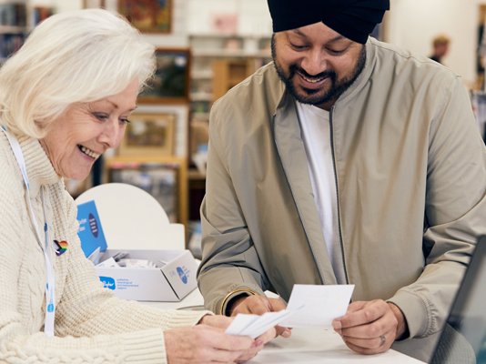 A Sue Ryder shop volunteer serving a customer at the till